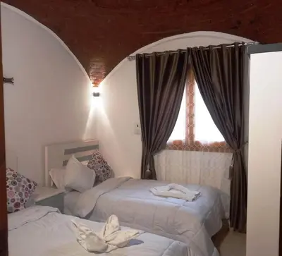 a bedroom with two beds in front of a window at Upper Egypt House in Luxor