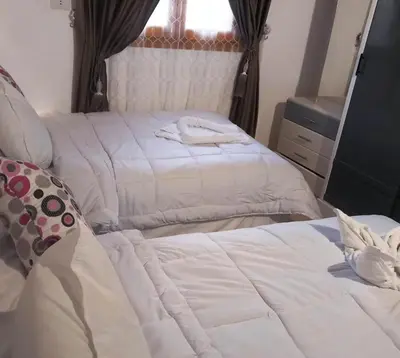 a bedroom with two beds with white sheets at Upper Egypt House in Luxor