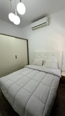 a bedroom with a large white bed with two lights at A 2 BR with pool view Hurghada in Hurghada