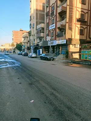 an empty city street with parked cars and buildings at وسط البلد البلدوزر بجوار مستشفي النيل التخصصي in Aswan