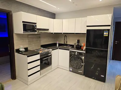 a kitchen with white cabinets and black appliances at قرية الهمبرا السياحية بالغردقة in Hurghada