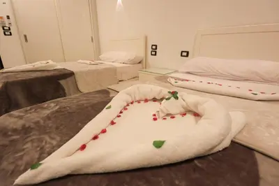 a room with two beds and a white blanket with cherries at Villa Abo Tarek in Al Aqālitah