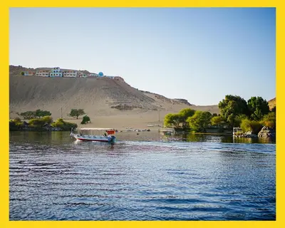 a boat floating on a river with a hill in the background at Anoosh camp in Aswan