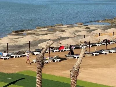 a beach with umbrellas and people on the beach at Al-Kiam Villa A F in Hurghada