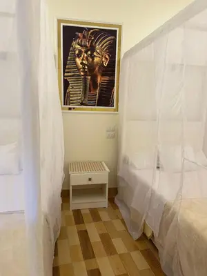 a bedroom with a bed and a painting of anubis at TibaHouse in Luxor