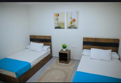 a bedroom with two beds and a table with a plant at Scandic Hurghada 323 in Hurghada