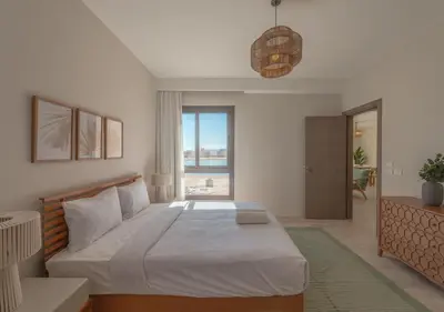 a bedroom with a large bed and a large window at Ancient Hill 3BR Gouna Sea View & Priv Roof Pool in El Gouna