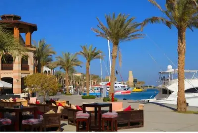 a resort with palm trees and tables and a marina at Marsa Alam Port Ghalib in Marsa Alam