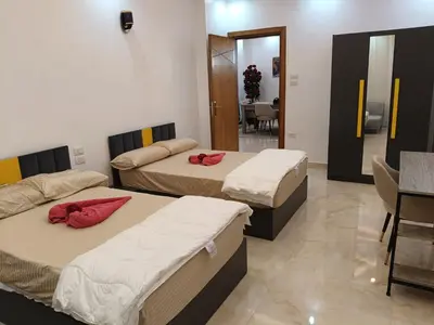 a room with three beds and a dining room at Aswan Nile View Dreams in Aswan