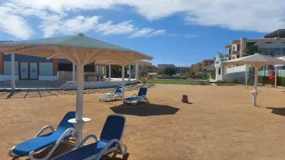 a group of chairs and umbrellas on a beach at Selina Bay Resort in El Gouna