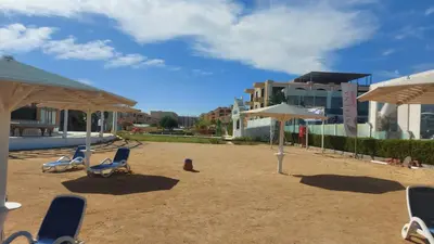 a group of chairs and umbrellas on a beach at Selina Bay Resort in El Gouna