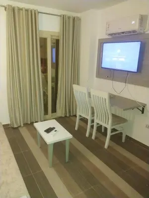 a living room with a table and two chairs and a television at Royal residence in Marsa Alam