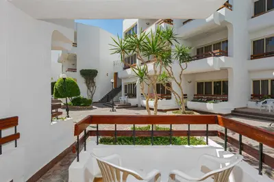 a balcony with white chairs and a building at Marlin Inn Azur Resort in Hurghada
