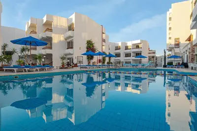 a swimming pool with blue umbrellas and some buildings at Marlin Inn Azur Resort in Hurghada