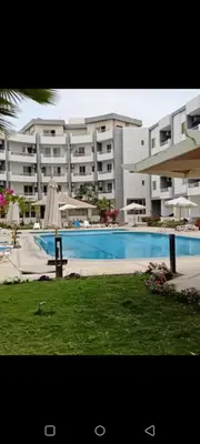 a large apartment complex with a swimming pool and an umbrella at Enter compound in Hurghada