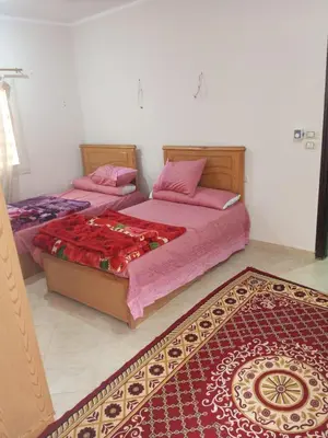 two beds in a bedroom with a rug at Eslam apartment 2 in Hurghada