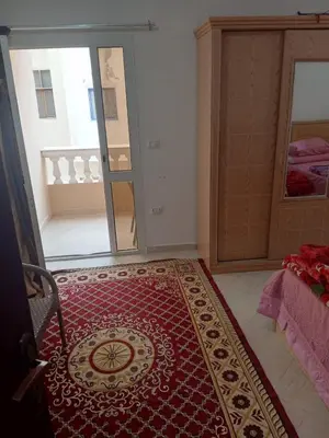 a room with a red rug on the floor next to a bedroom at Eslam Apartments in Hurghada