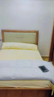 a bed with a wooden headboard and a book on it at Eslam Apartments in Hurghada