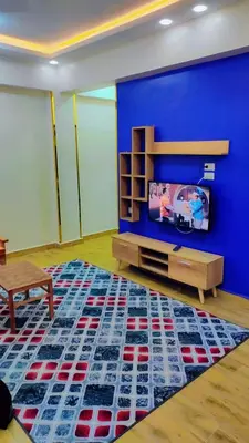 a living room with a blue wall and a tv at Eslam Apartments in Hurghada