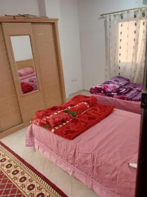 a bedroom with two beds with pink sheets and a mirror at Eslam Apartments in Hurghada