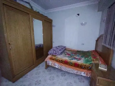 a small bedroom with a bed and a cabinet at جبل تقوق فيلا عبدالله محروس in Nag` el-Ramla