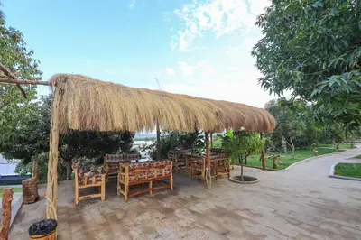 a patio with tables and chairs under a straw umbrella at Eden on the Nile in Luxor