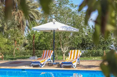 two chairs and an umbrella next to a pool at Eden on the Nile in Luxor