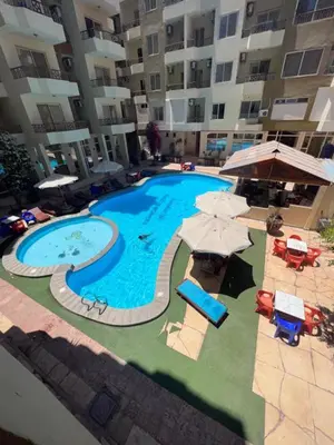 a large swimming pool with umbrellas and chairs next to a building at Paradise Hill in Hurghada