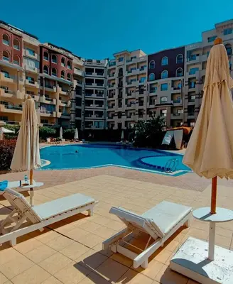 a swimming pool with two lounge chairs and umbrellas at Luxury Sea view studio in Hurghada