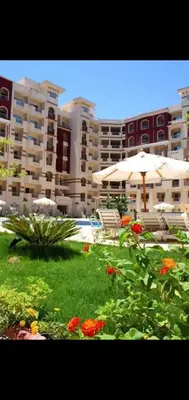 a patio with an umbrella and flowers in front of a building at Luxury Sea view studio in Hurghada