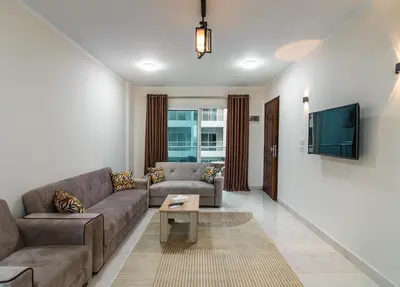a living room with a couch and a tv at Luxury City Center One-Bedroom Suite by Peaks in Hurghada