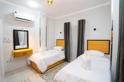 a bedroom with two beds and a mirror at Eldeak Hotel Apartments in Luxor