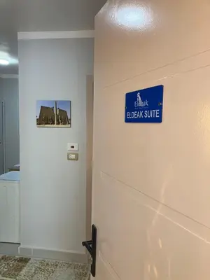 a door with a blue sign on a wall at Eldeak Hotel Apartments in Luxor