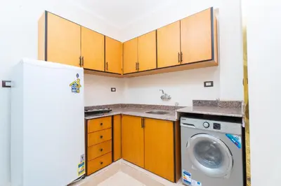 a kitchen with a refrigerator and a washing machine at Eldeak Hotel Apartments in Luxor