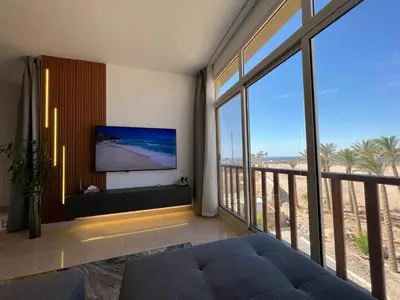 a living room with a tv and a large window at Exklusives Apartment mit Dachterrasse und Meerblick in Hurghada