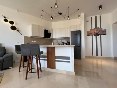 a kitchen with a bar with chairs and a refrigerator at Exklusives Apartment mit Dachterrasse und Meerblick in Hurghada
