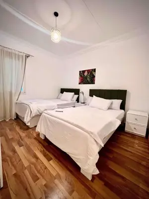 a bedroom with two beds with white sheets and wood floors at Touristic Center in Hurghada
