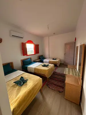 a room with three beds and a couch in it at Palm Guest House in Aswan