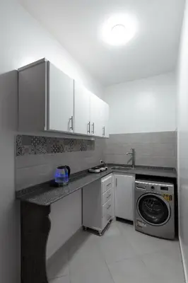 a kitchen with white cabinets and a washer and dryer at Pharaohs Guest House in Luxor