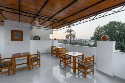 a restaurant with wooden tables and chairs and a balcony at Pharaohs Guest House in Luxor