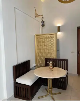 a table and a bench in a room with a table at Serene Apartment Makadi Heights in Hurghada