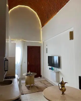 a kitchen with a table and a tv in a room at Serene Apartment Makadi Heights in Hurghada