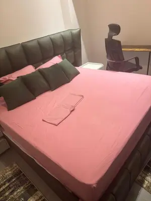 a large bed with pink sheets and a chair at luxury apartment Makadi heights phase 2 in Hurghada
