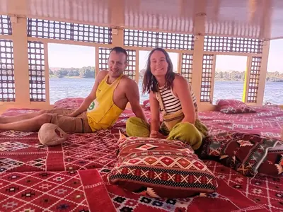 a man and a woman sitting on a bed at Hamdy's Felouque in Aswan