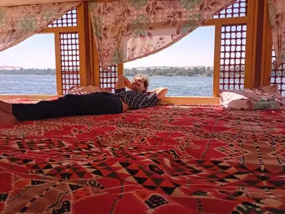 a man laying on a bed in a boat at Hamdy's Felouque in Aswan