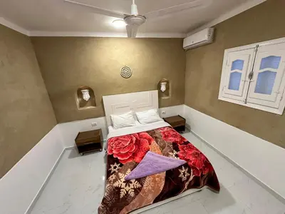 a bedroom with a bed with a floral blanket on it at Tuya House Luxor in Luxor
