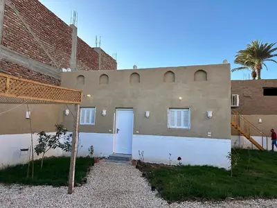a house with a white door and a brick building at Tuya House Luxor in Luxor