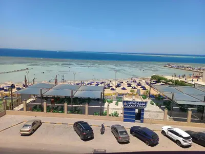 a parking lot with cars parked in front of a beach at شقة فندقية على البحر مباشرا 2 in Hurghada