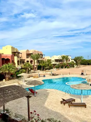a view of a resort pool with tables and umbrellas at Sunshine Y1-1-7 in Hurghada