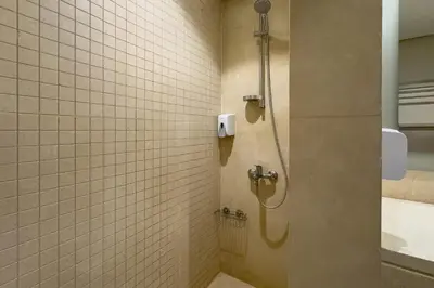 a shower in a bathroom with white tiles at Remarkable & Rare 2BDR Mangroovy Free Pool & Beach in Hurghada